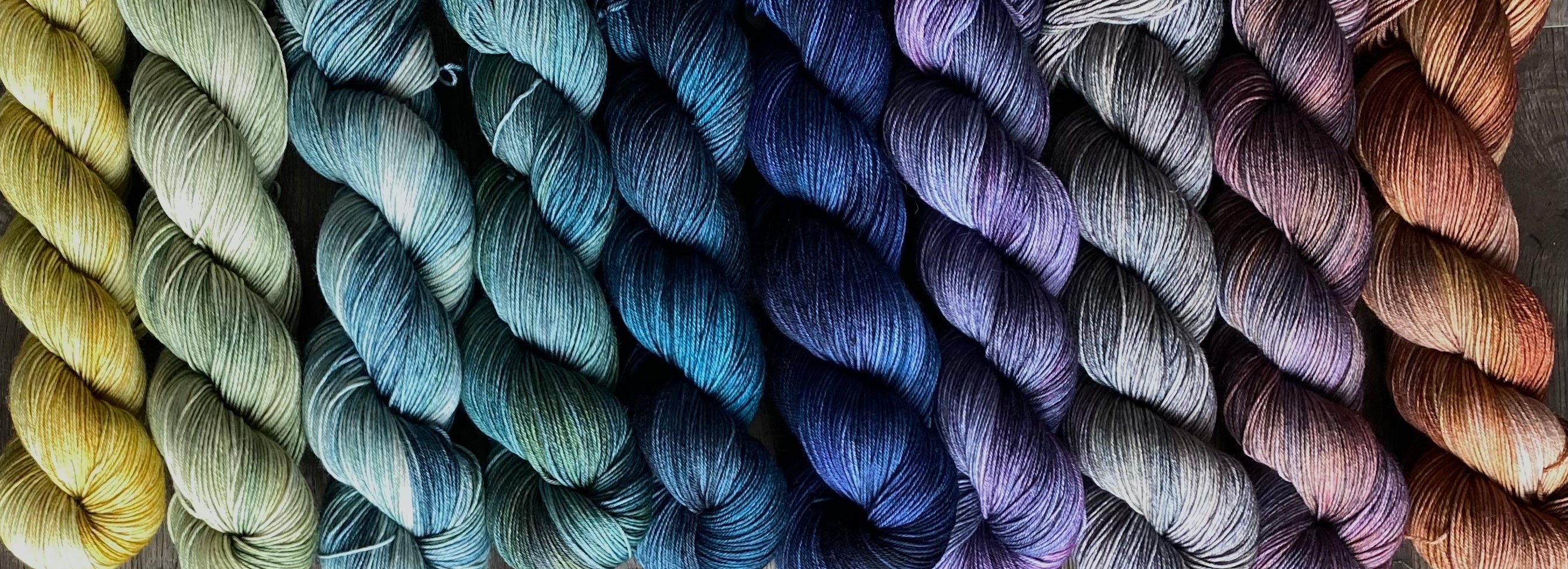 Colorful yarn skeins with a knitted swatch on a textured surface